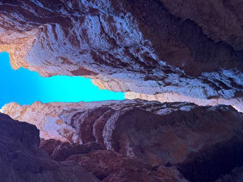 Narrow canyon walls with bright blue sky above.