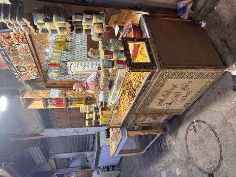       A woman selling sweets and jars in a market stall.
  