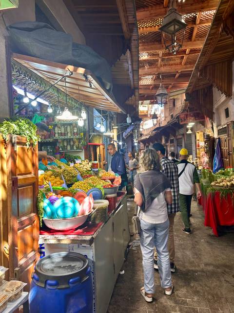 Market with various fruits and goods displayed under bright lights.