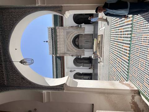       An elegantly designed courtyard with arches and people visiting.
  
