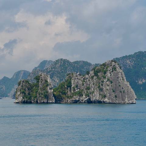 Rocky limestone formations covered with lush vegetation on a bay.