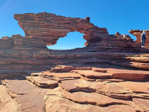 Red sandstone rock formation with a natural arch opening.