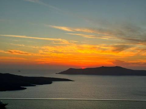 Vibrant sunset over the sea with silhouetted islands.