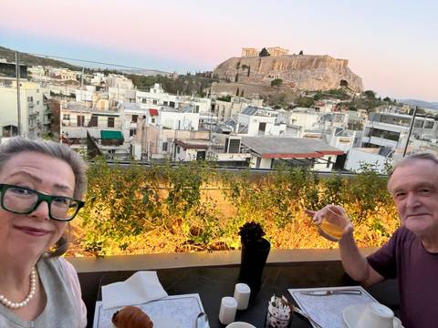 Couple enjoying drinks with Acropolis in the background.
