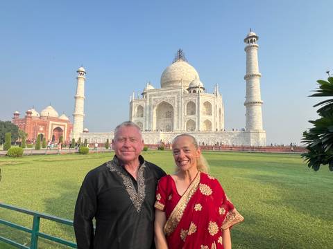       Couple posing in traditional attire in front of the Taj Mahal.
  
