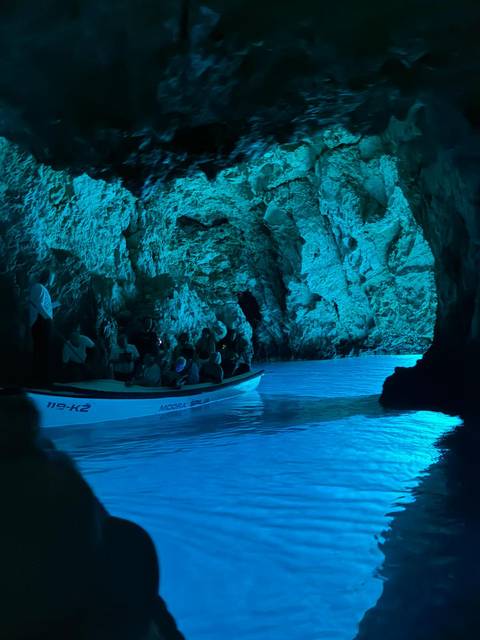       Boat tour inside a blue lit cave.
  