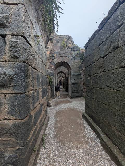       Arched stone corridor with tourists.
  
