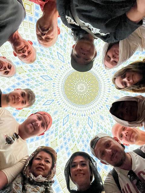 People looking up at a beautifully decorated dome.