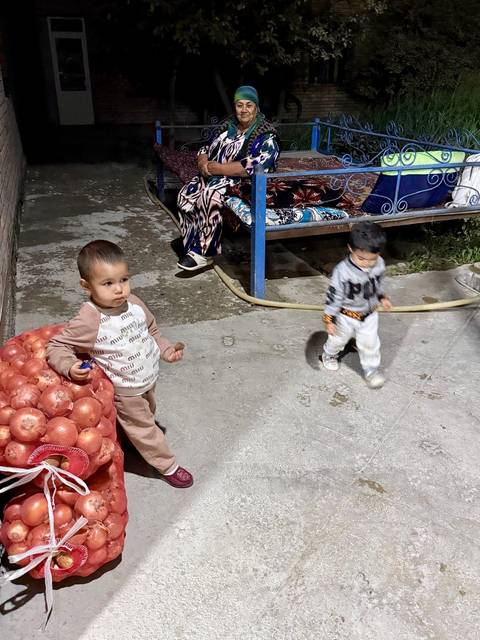 Small children playing near a sack of onions.