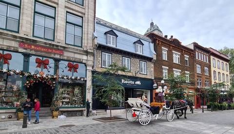 Street in Quebec City with traditional shops and a horse-drawn carriage.