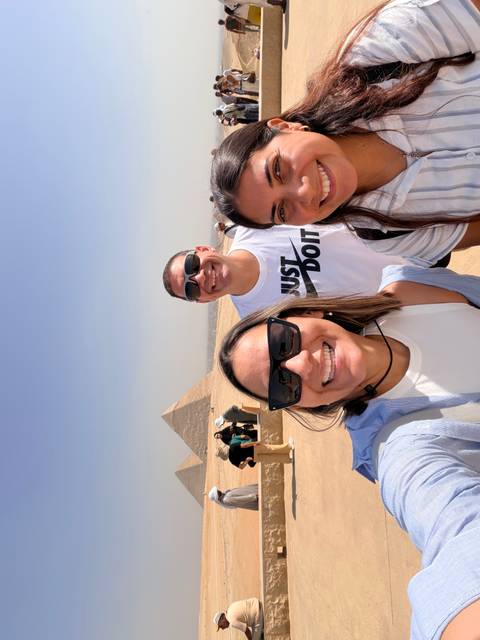 A group of people smiling with the pyramids in the background.