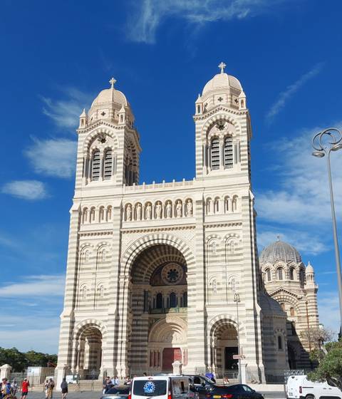 Large cathedral with striped facade and two towers.
