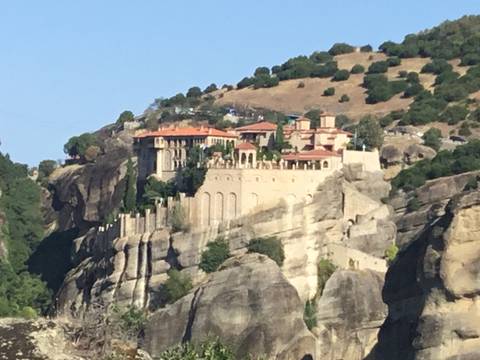       A monastery perched on a rock formation surrounded by greenery.
  
