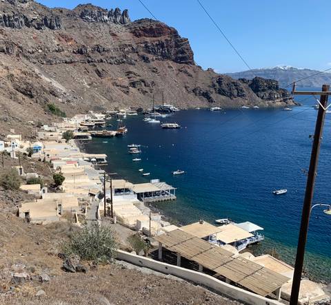       Coastal village by a deep blue sea with boats and rugged terrain.
  