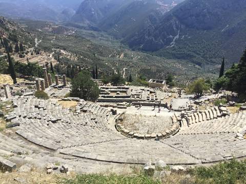       Ancient amphitheater ruins set in a lush green valley.
  