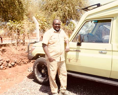       Guide standing beside a safari vehicle.
  
