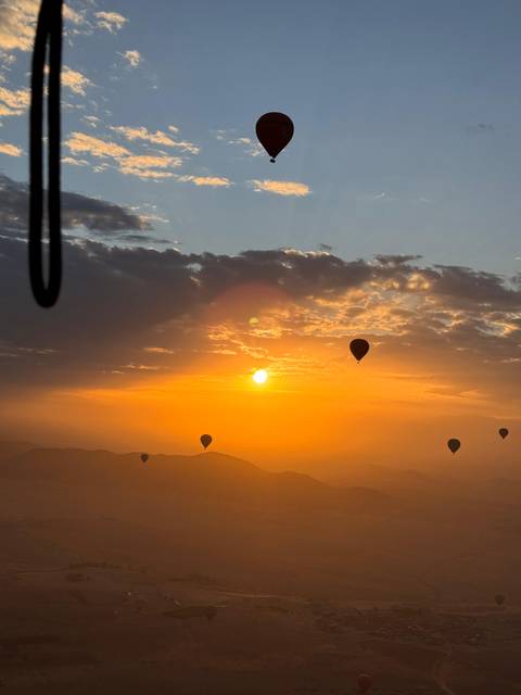 Hot air balloons floating at sunrise over a landscape.