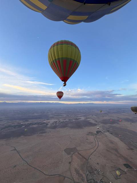 Hot air balloons flying over a vast landscape with mountains.