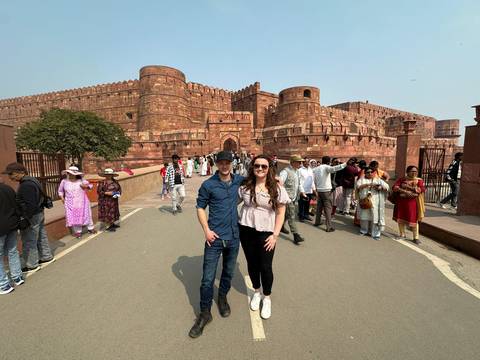 Tourists posing with the Red Fort in Agra as a backdrop.
