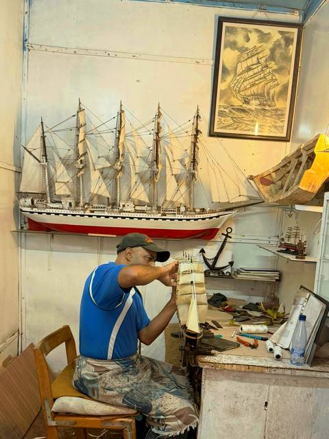 Man working on a model ship in a shop.