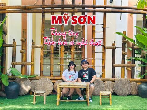       People sitting in front of a colorful sign and bamboo decor.
  