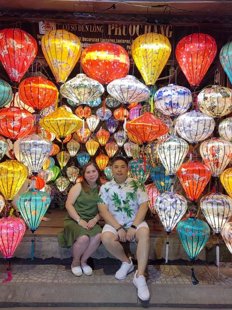       Couple sitting with colorful traditional lanterns in the background.
  
