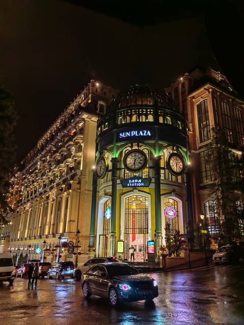       Illuminated building with clocks and colorful lights at night.
  