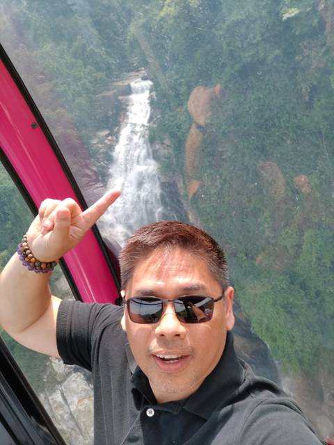       Close-up selfie with a waterfall visible through a vehicle window.
  