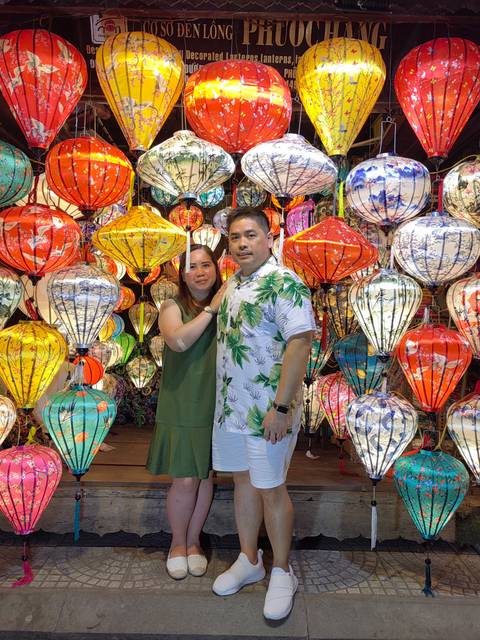       Couple standing with colorful traditional lanterns around them.
  