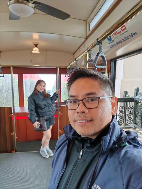       Two people inside a cable car with a city view in the background.
  