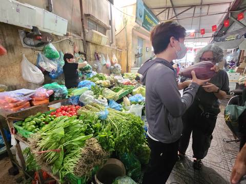       Local market scene with shoppers and vegetables.
  