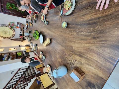       Long dining table with food and people dining.
  