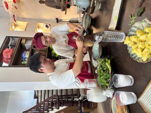 Two chefs preparing food with ingredients on a table.