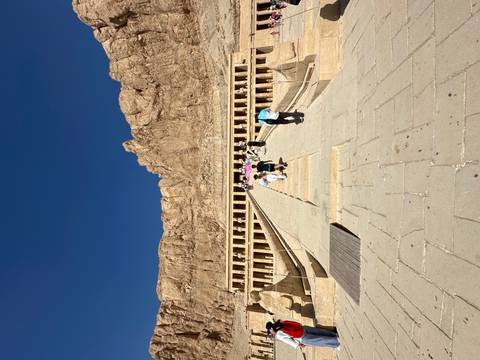 Tourists climbing the steps of an ancient Egyptian temple.