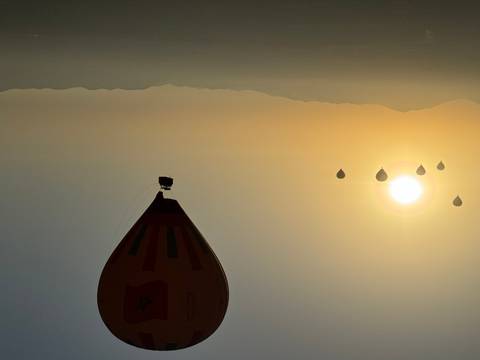 Hot air balloons flying over a landscape at sunrise.