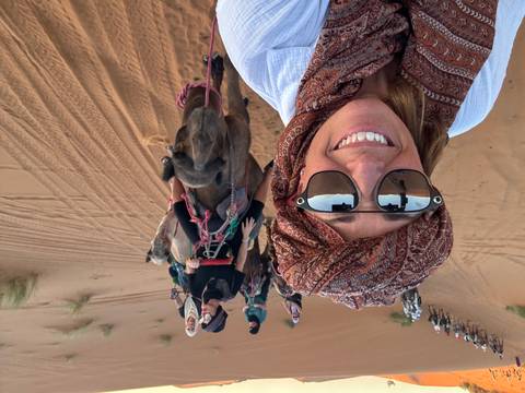 Group of tourists riding camels on a desert trek.
