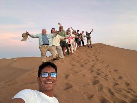 Group of people posing on top of a sand dune.
