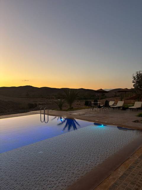 Swimming pool with lounge chairs overlooking desert hills.