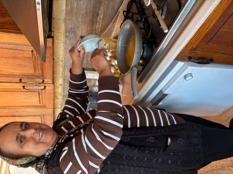 Person cooking in a kitchen with a frying pan on the stove.