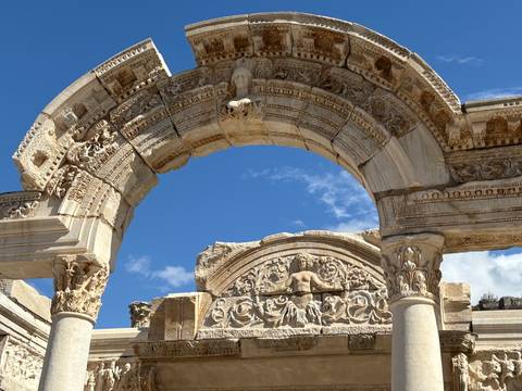       Intricate carvings on an ancient stone archway with clear skies.
  