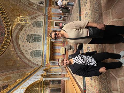       Two people in an ornate historical interior with intricate designs and arches.
  