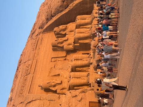 A large crowd of people in front of massive ancient Egyptian statues.