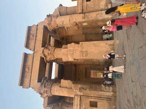 Visitors exploring an Egyptian temple with grand pillars.