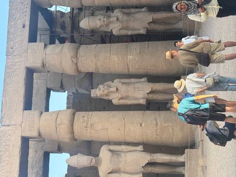 Tourists near large ancient temple statues in Egypt.