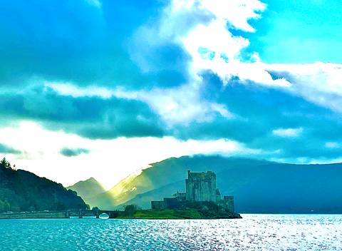       A scenic view of a castle by a loch with dramatic lighting.
  