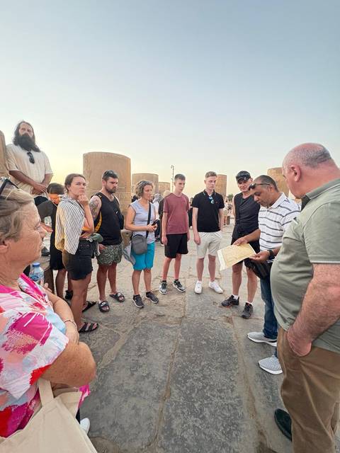 Tour group gathered around a guide with historical columns in the background.