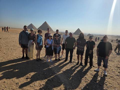       Group of people standing in front of the pyramids in Egypt.
  