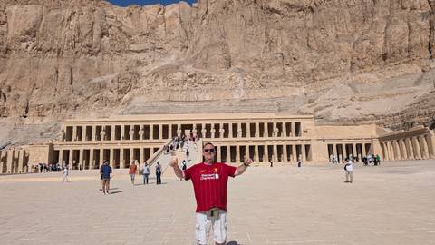 Person posing in front of the Mortuary Temple of Hatshepsut.