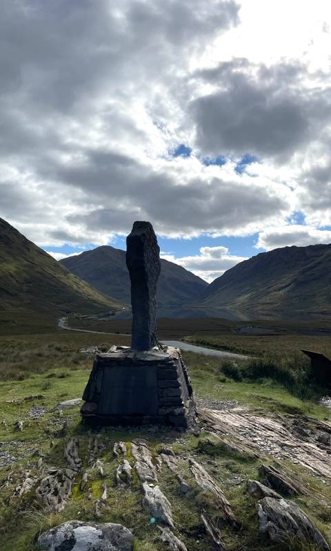       Standing stone in a mountainous valley landscape.
  