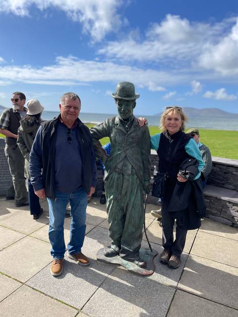       Couple standing next to a statue by the sea.
  